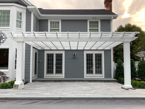 A beautiful white pergola attached to a gray house