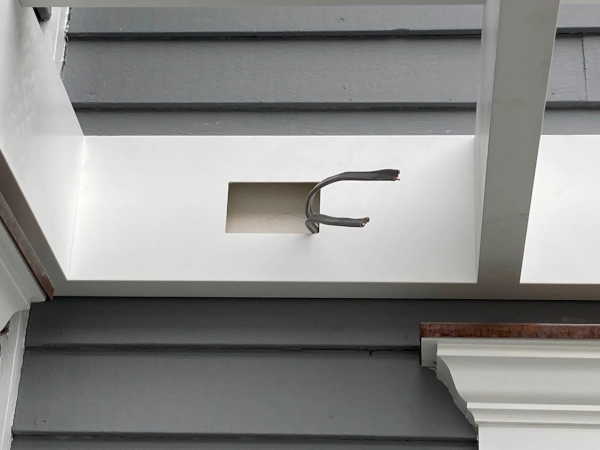 A beautiful white pergola attached to a gray house