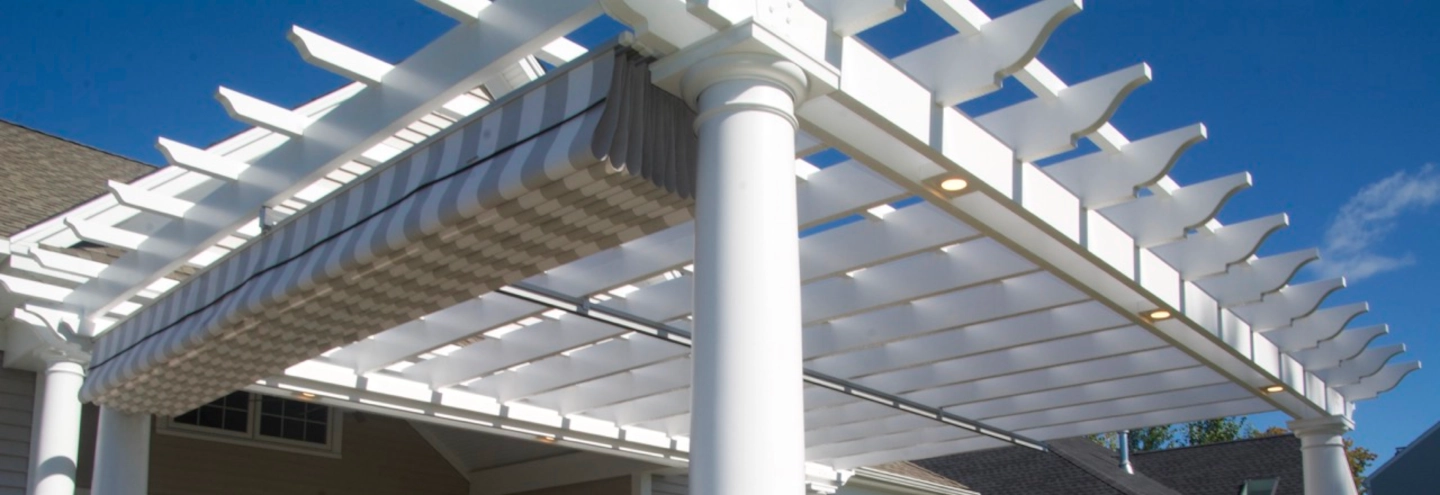 A pergola with a striped fabric roll-up shade