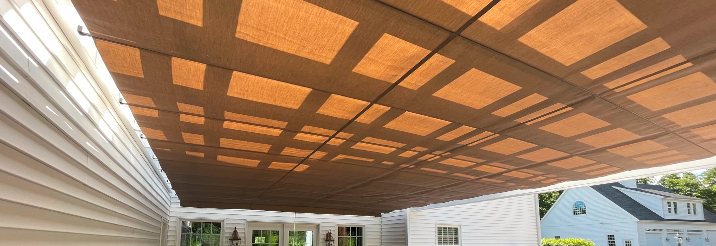 A pergola with a striped fabric roll-up shade