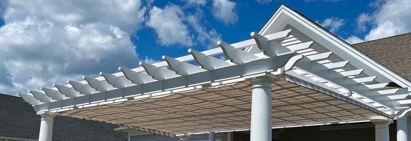 A pergola with a striped fabric roll-up shade